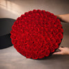 Round black box filled with 99 red preserved roses 