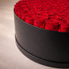 Black round box filled with 99  red preserved everlasting roses
