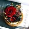 Decorative preserved flower arrangement with red and brown roses on a wooden base
