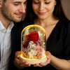 Couple holding a glass dome with preserved flowers and a red rose.