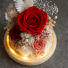 Decorative arrangement of red and pink roses with dried flowers on a round wooden base.