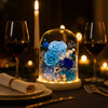 Decorative glass dome with blue roses on a romantic dinner table setting.