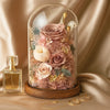 Glass dome with preserved flowers on a beige fabric background