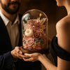Two people holding a glass dome with preserved flowers
