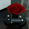 Red rose in a black holder with 'Mom I love you' card on a reflective surface